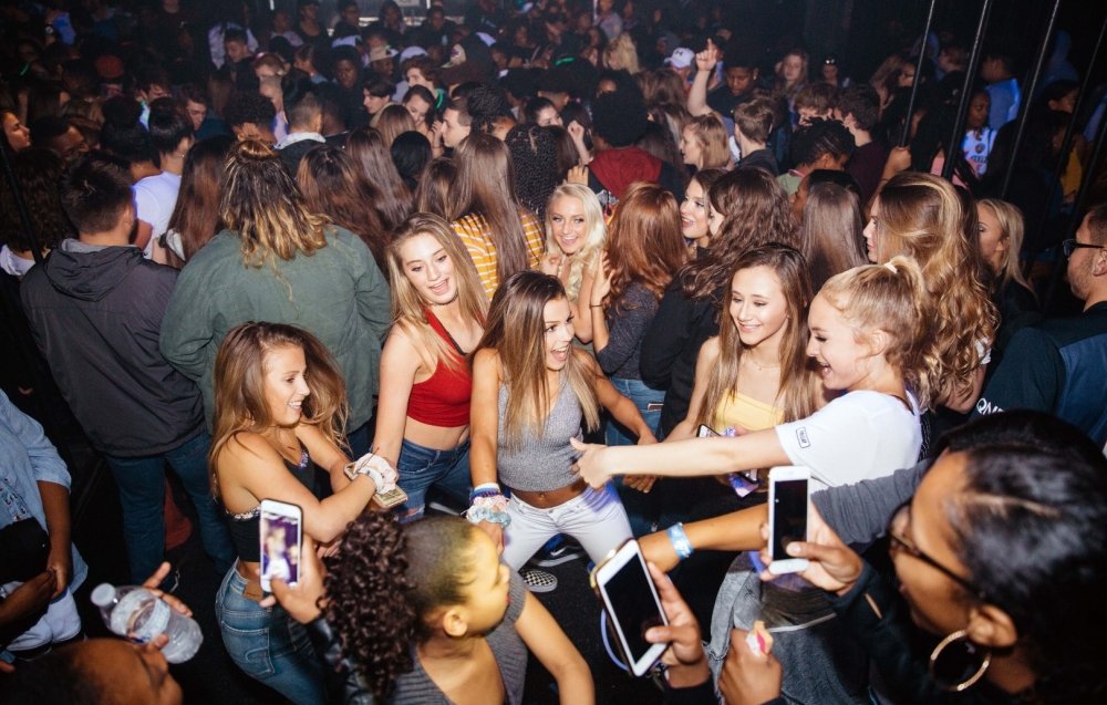 High School Dance DJ Hire - Students With Their hand in the air dancing and at the same time holding their mobile phones