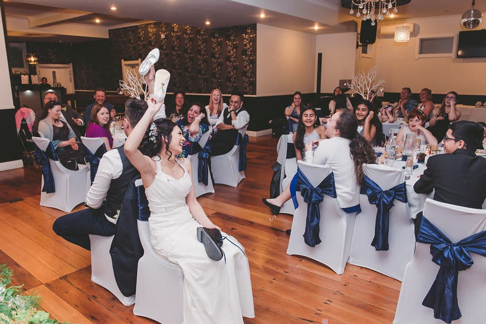 Shoe game conducted by MC scott at Gibson wedding - bride and groom with guests watching